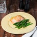 A Libbey farmhouse porcelain plate with a piece of salmon, green beans, and a fork and knife on a table.