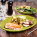 A Fiesta Lemongrass oval china platter with salmon and vegetables on a table.