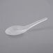 A clear plastic Visions Asian soup spoon on a gray surface.