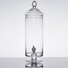 A clear glass Fifth Avenue Crystal beverage dispenser with a black lid and spigot.