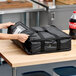 A black soft-sided insulated pizza delivery bag made of heavy-duty nylon, designed to hold up to two 16-inch pizza boxes or one 18-inch pizza box.