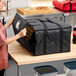 A large black insulated pizza delivery bag made of heavy-duty nylon, designed to hold multiple pizza boxes.