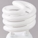 A close-up of a Satco warm white spiral light bulb.