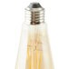 A Satco transparent amber LED light bulb with a yellow filament inside and a silver cap.
