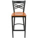 A Lancaster Table & Seating black cross back bar stool with a cherry wood seat.