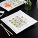 Two CAC porcelain plates with sushi rolls and chopsticks on a table.