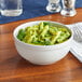 A close-up of a bowl of pasta with pesto sauce in an Acopa Bright White stoneware bowl.