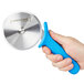A hand holding a Dexter-Russell blue plastic pizza cutter with a high-heat handle.