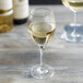 A Stolzle dessert wine glass filled with white wine on a table.