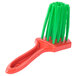 A close-up of a red and green Prince Castle Saber King cleaning brush.