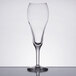 A Libbey tulip champagne glass with a small amount of liquid in it.