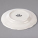 A white Tuxton china plate with black scalloped edges.