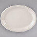 A white oval Tuxton china platter with a scalloped edge.