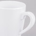 A close-up of a white mug with a white handle.