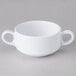 A white Elite Global Solutions melamine cup with two handles.