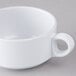 A close-up of a white Elite Global Solutions melamine cup with two handles.