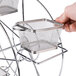 A hand holding a metal mesh basket on a Clipper Mill Ferris Wheel rack.
