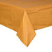 A table with a Creative Converting Pumpkin Spice Orange plastic table cover.