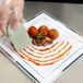 A person using a Mercer Culinary square notch silicone plating tool to plate food.