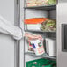 A person taking a white container of food from an Avantco reach-in refrigerator.