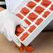 A gloved hand holding a tray of red Martellato tangerine slice molds.