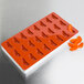 A red silicone Martellato mold with orange fruit shaped compartments.