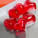 A group of red heart-shaped jelly molds on a metal surface.