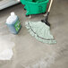 A green Rubbermaid mop head in a bucket of detergent next to a green Rubbermaid bucket.