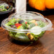 A clear plastic dome lid on a bowl of salad.