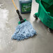 A blue Rubbermaid wet mop head with a green handle in a green bucket.