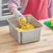 A person putting corn on the cob in a Choice 1/2 Size stainless steel perforated hotel pan.
