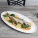 A fish with vegetables on a white Libbey porcelain tray.