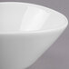 A close up of a Libbey white porcelain bowl with a curved edge on a gray surface.