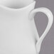A close up of a Libbey Royal Rideau white porcelain creamer with a handle.