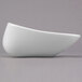 A white Libbey square porcelain bowl with curved edges on a grey surface.