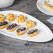 A Libbey white porcelain plate with chocolate covered pastries on a table.