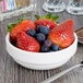 A Libbey Royal Rideau white porcelain bowl filled with strawberries and blueberries on a table.