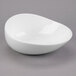 A white Libbey round porcelain bowl with a curved shape on a gray surface.