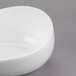 A Libbey Royal Rideau white porcelain bowl with a curved edge on a gray surface.