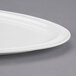 A close-up of a Libbey Royal Rideau white porcelain triform platter with a curved edge.