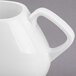 A close-up of a Libbey white porcelain creamer with a handle.