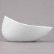 A Libbey Royal Rideau white porcelain bowl with a curved shape on a gray surface.