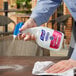 A hand using Purell Foodservice Surface Sanitizer to spray and clean a table.
