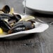 A white Libbey porcelain platter with mussels and lemon slices.
