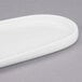 A white oval shaped porcelain tray with a curved edge.