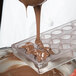 Liquid chocolate being poured into a Chocolate World plastic mold.