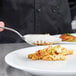 A chef using a Mercer Culinary plating spoon to plate pasta.