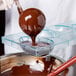 Liquid chocolate being poured into a Matfer Bourgeat egg chocolate mold.