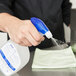 A hand spraying Purell Foodservice Surface Sanitizer onto a counter.