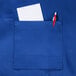 A royal blue Chef Revival bib apron with a pocket holding a pen and paper.